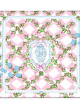 A square decorative Mahjong mat with a pink and white diamond pattern, green holly leaves, and red berries, featuring a central blue and white crest surrounded by a pink bow. Light blue Mahjong tiles are scattered around it on a white background.