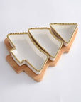 Set of four white ceramic trays with gold rims on a wooden stand against a white background