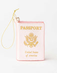 A novelty Christmas ornament shaped like a pink passport with gold foil-style lettering and emblem, complete with a gold hanging string, shown on a plain white background.