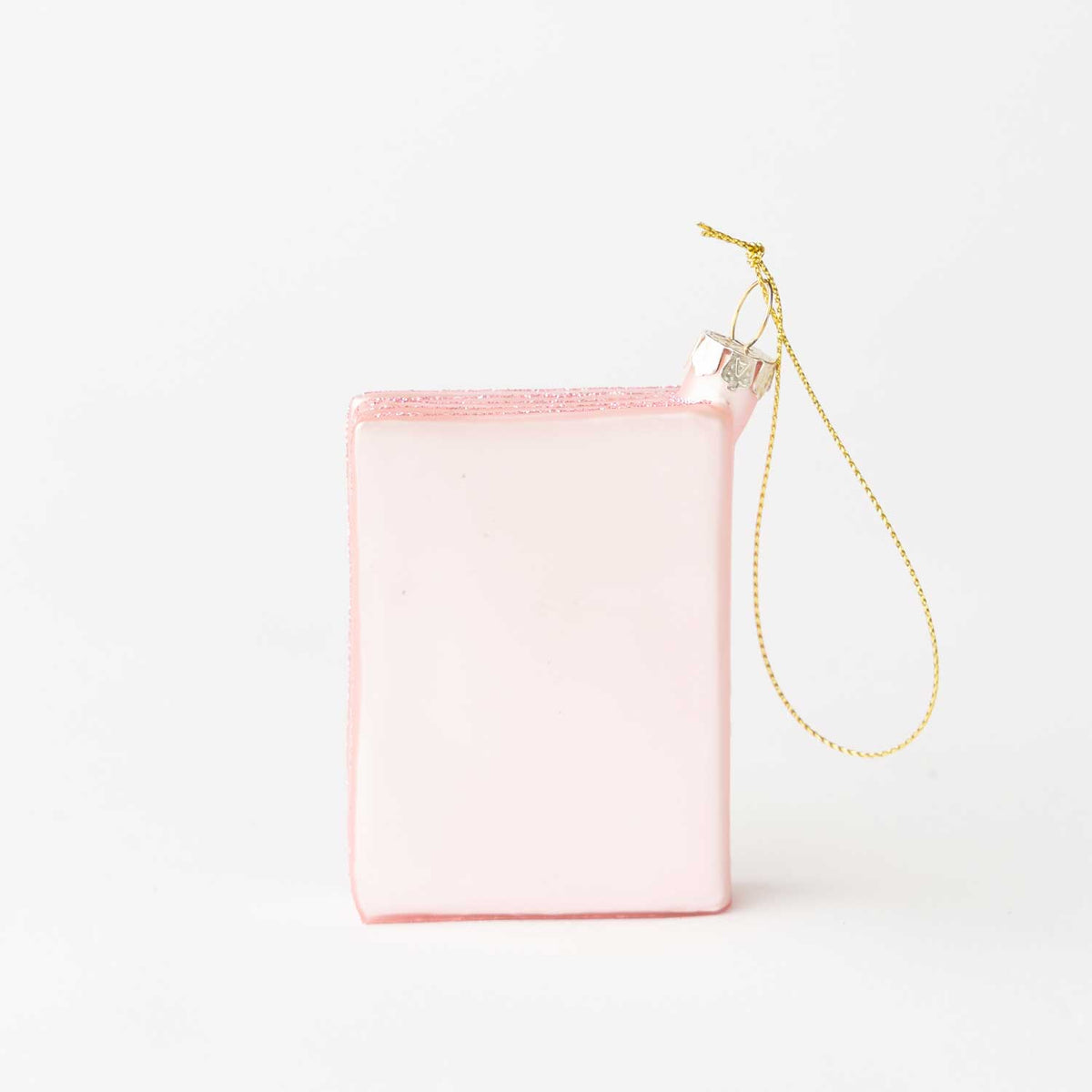 The backside of the pink passport ornament with a gold hanging loop, photographed on a clean white background.