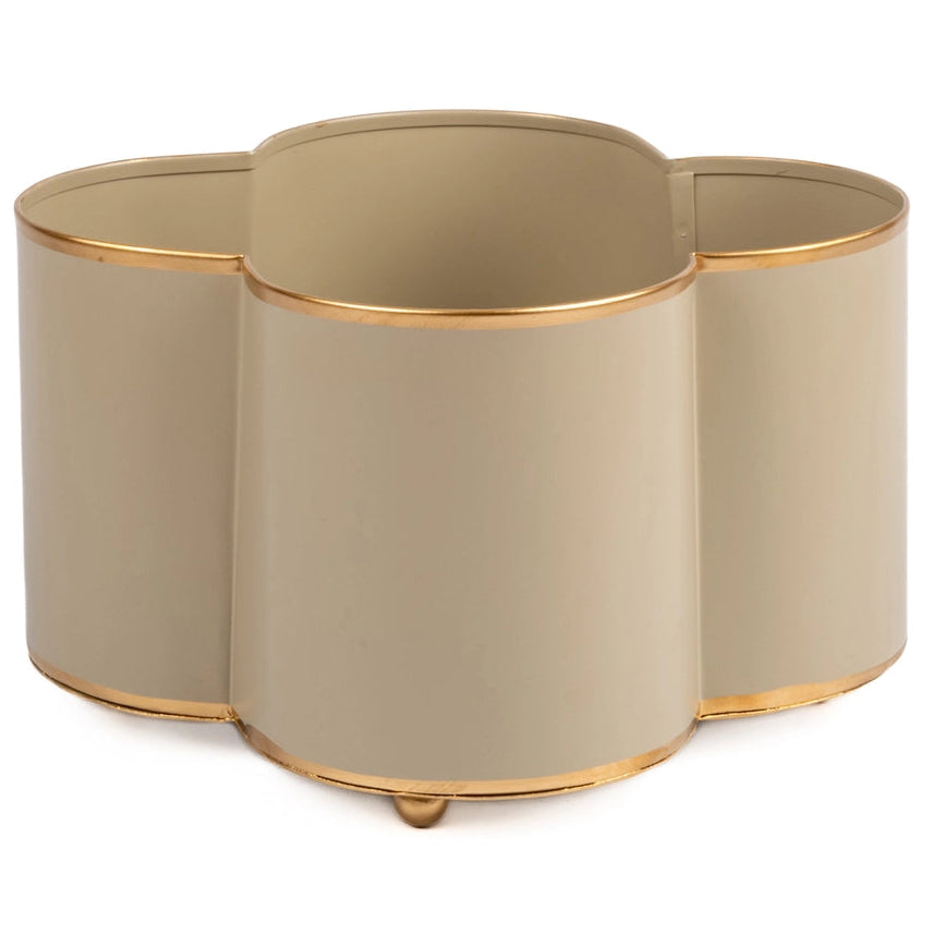 A beige cachepot with gold trim detail feet, designed in a quatrefoil shape with four round openings for plant pots.