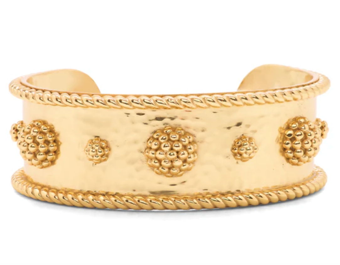 A gold-colored cuff bracelet with a bold design featuring golden berries and rope trim.