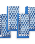 A set of four blue and white cloth napkins with a geometric block print pattern.