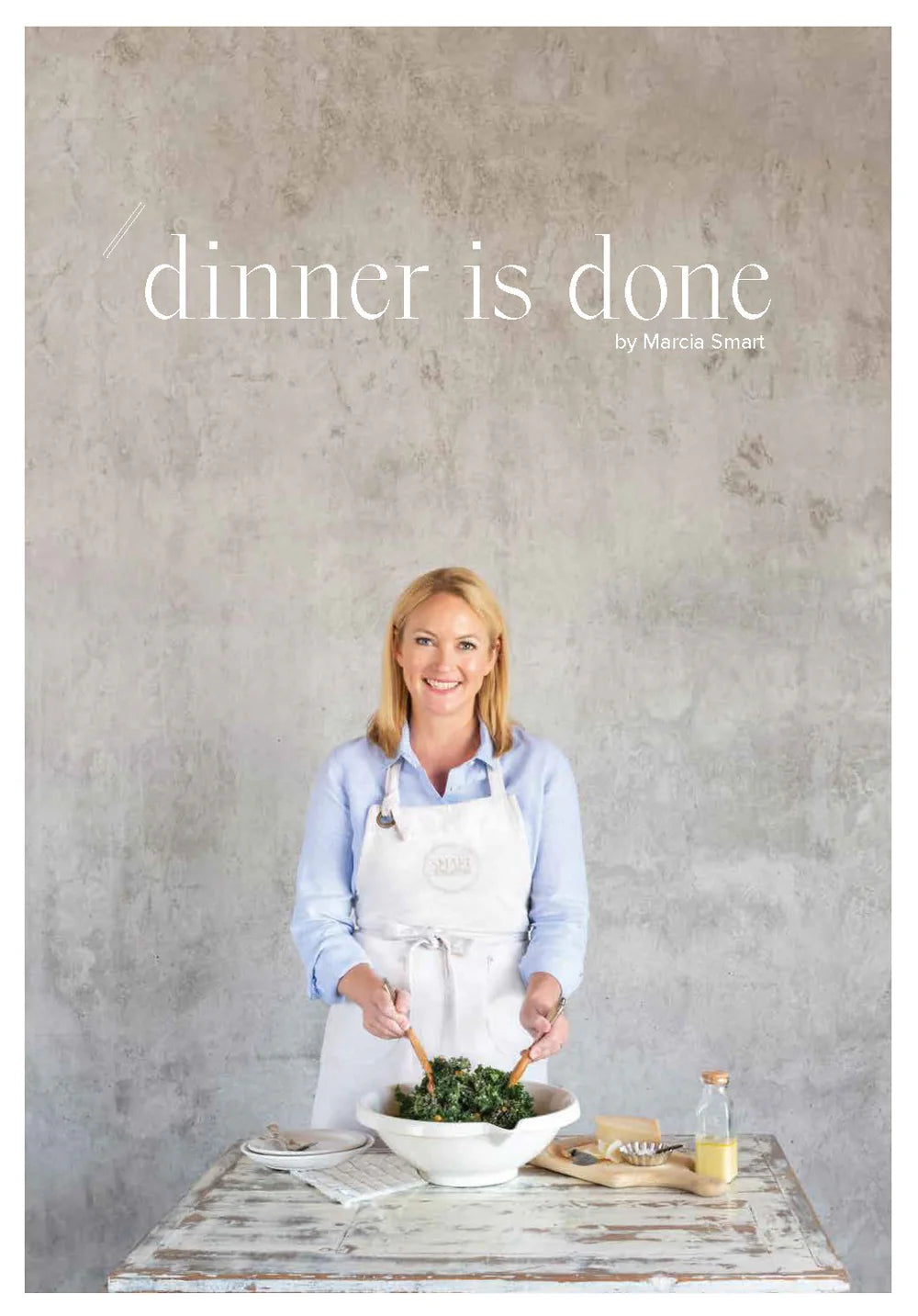 The cover of the cookbook 'Dinner is Done by Marcia Smart' featuring the author in a kitchen setting with a salad.