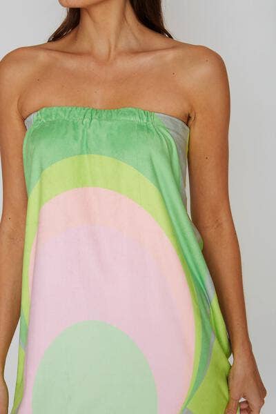 Woman wearing a towel wrap with green and pink abstract pattern on a plain background