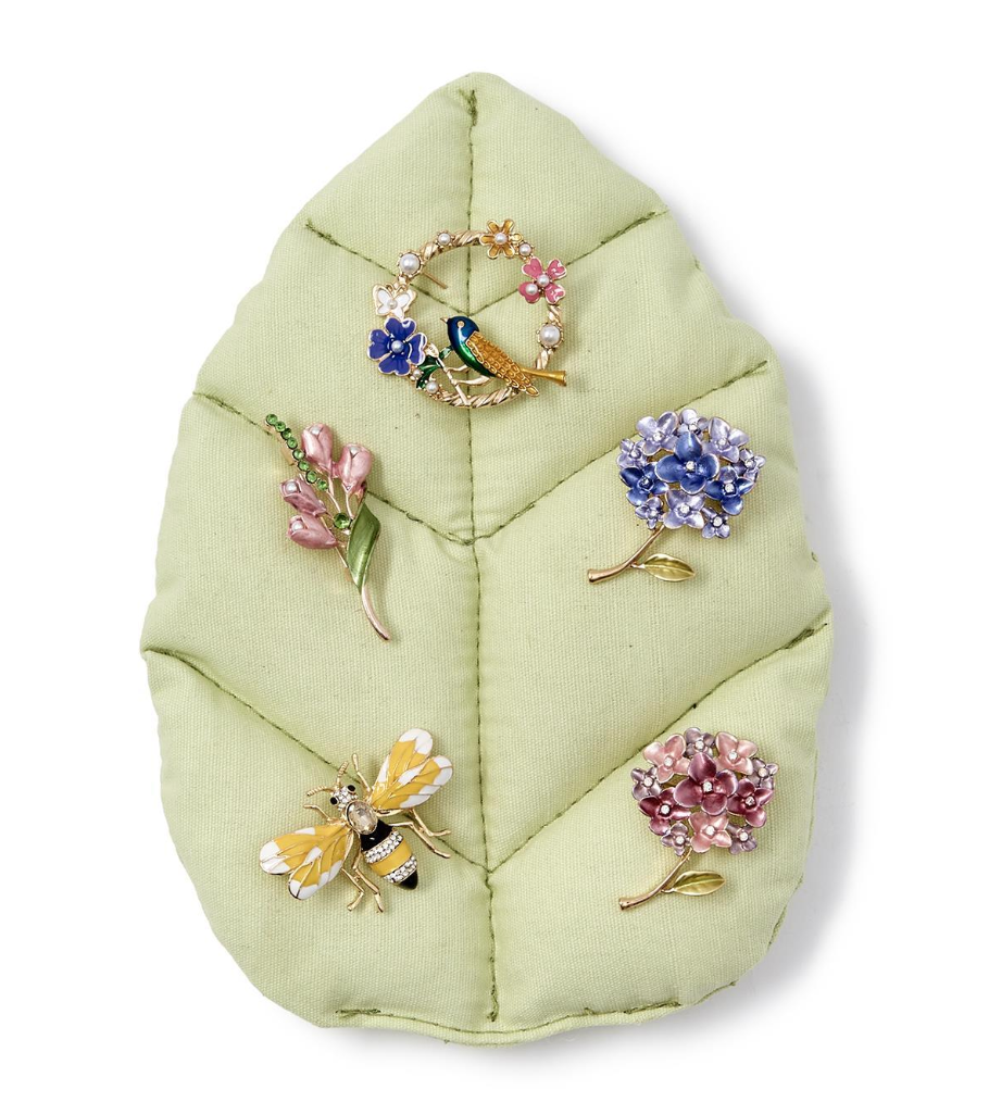 Assortment of Enchanted Brooch Pins on green leaf.