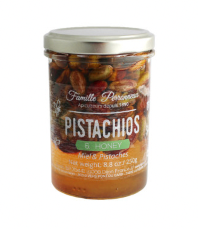 Jar of pistachios and honey with a silver lid on a white background