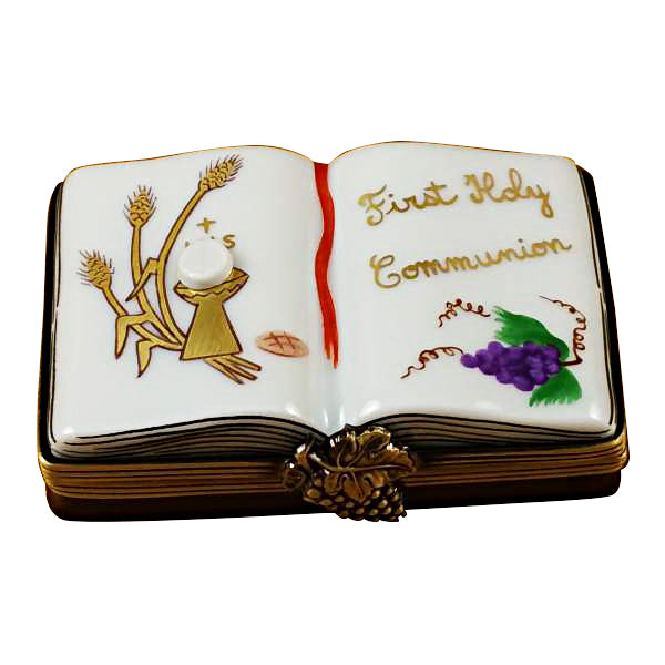 A hand-painted porcelain Limoges box depicting a book with 'First Holy Communion' text and religious symbols, measures 2.5 inches by 1.
