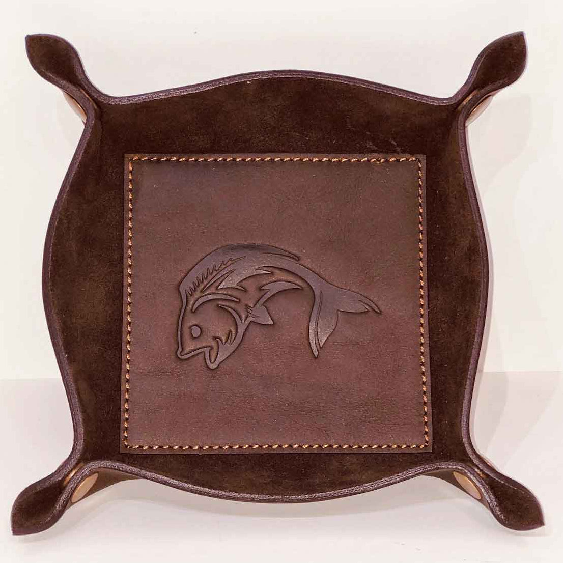 Brown leather tray with fish emblem on a white background