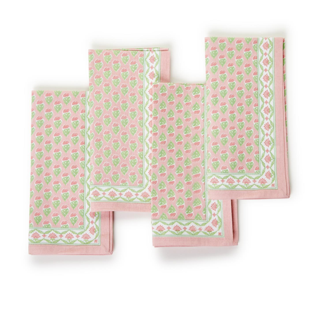 A set of four pink cloth napkins with green and white floral block prints, displayed unfolded.