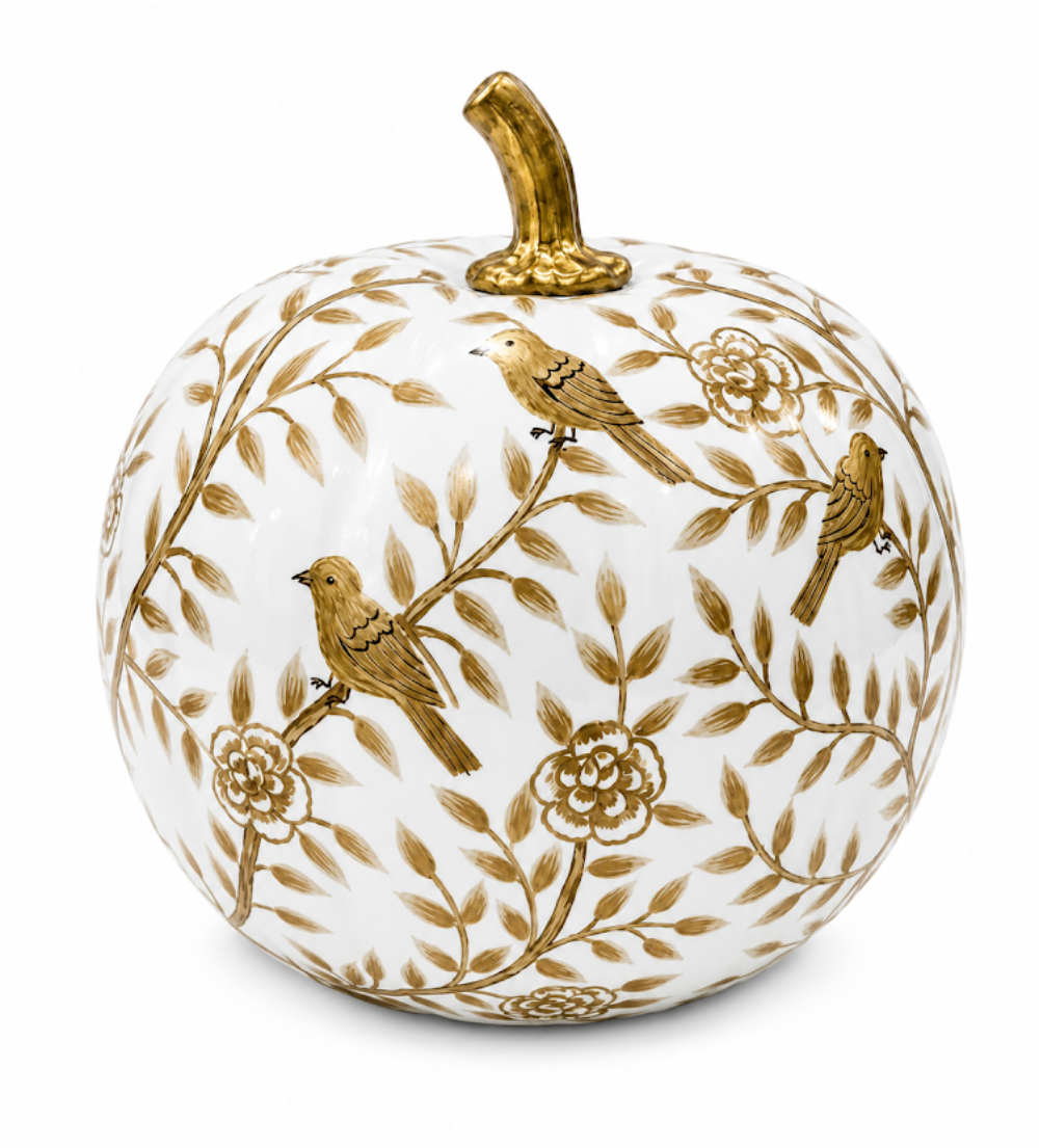 A decorative ceramic pumpkin with a white body, decorated with gold-toned floral branches and three small gold birds, topped with a gold stem, on a white background.