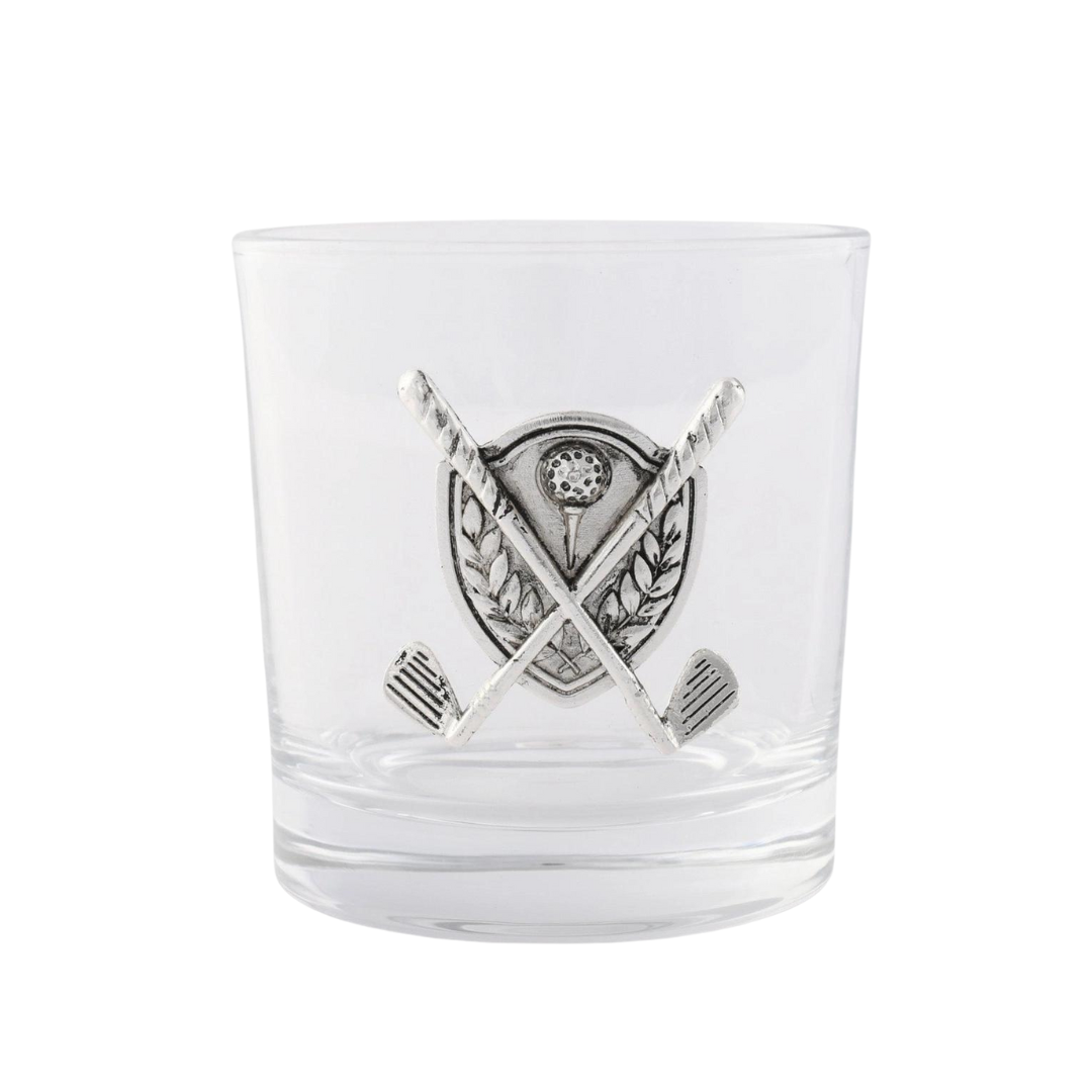 A clear glass with a metal golf ball and clubs design embedded on its surface.