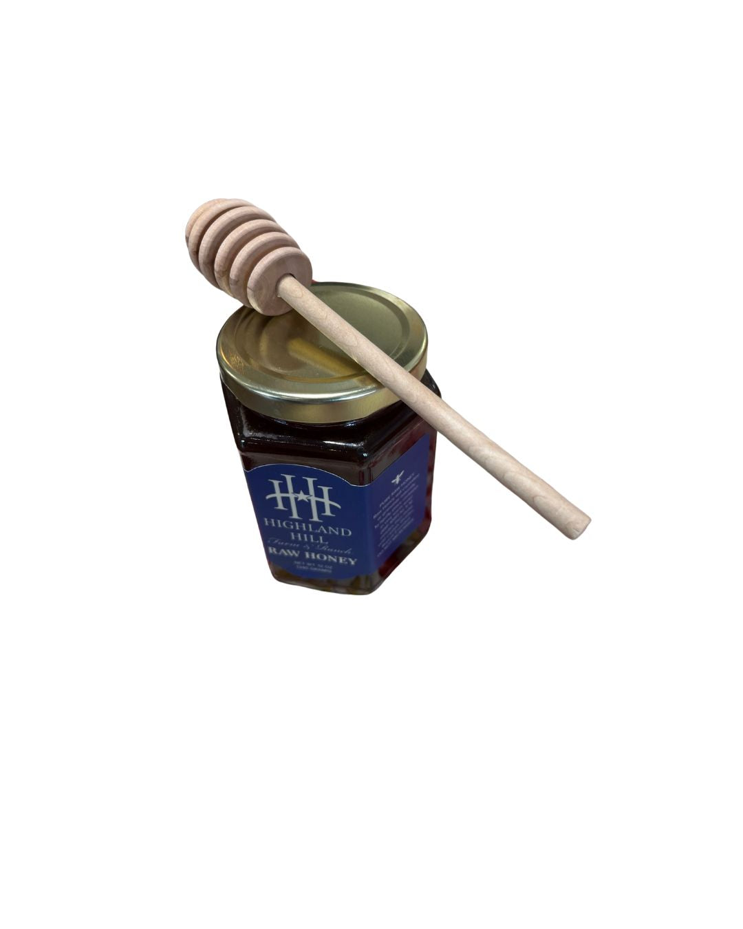 A jar of Highland Hill raw honey with a wooden dipper resting on top.