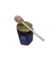 A jar of Highland Hill raw honey with a wooden dipper resting on top.