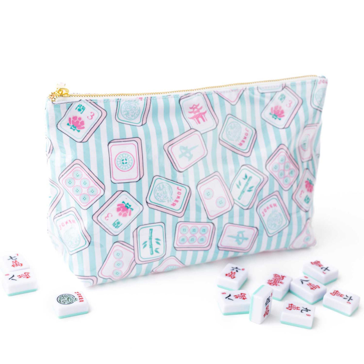 A zippered pouch with a light blue and white striped background and an all-over print of pink and white mahjong tiles. Several loose mahjong tiles are scattered on the white surface in front of the pouch.