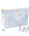 A zippered pouch with a light blue and white striped background and an all-over print of pink and white mahjong tiles. Several loose mahjong tiles are scattered on the white surface in front of the pouch.