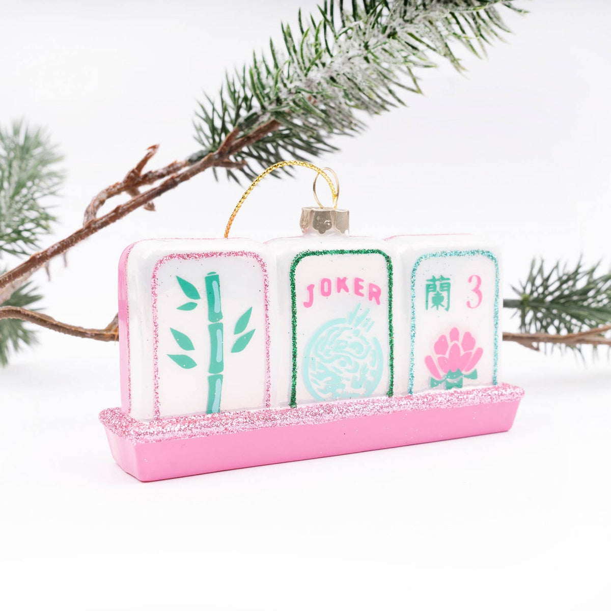 Decorative mahjong ornament with pink stand and card designs on a white background