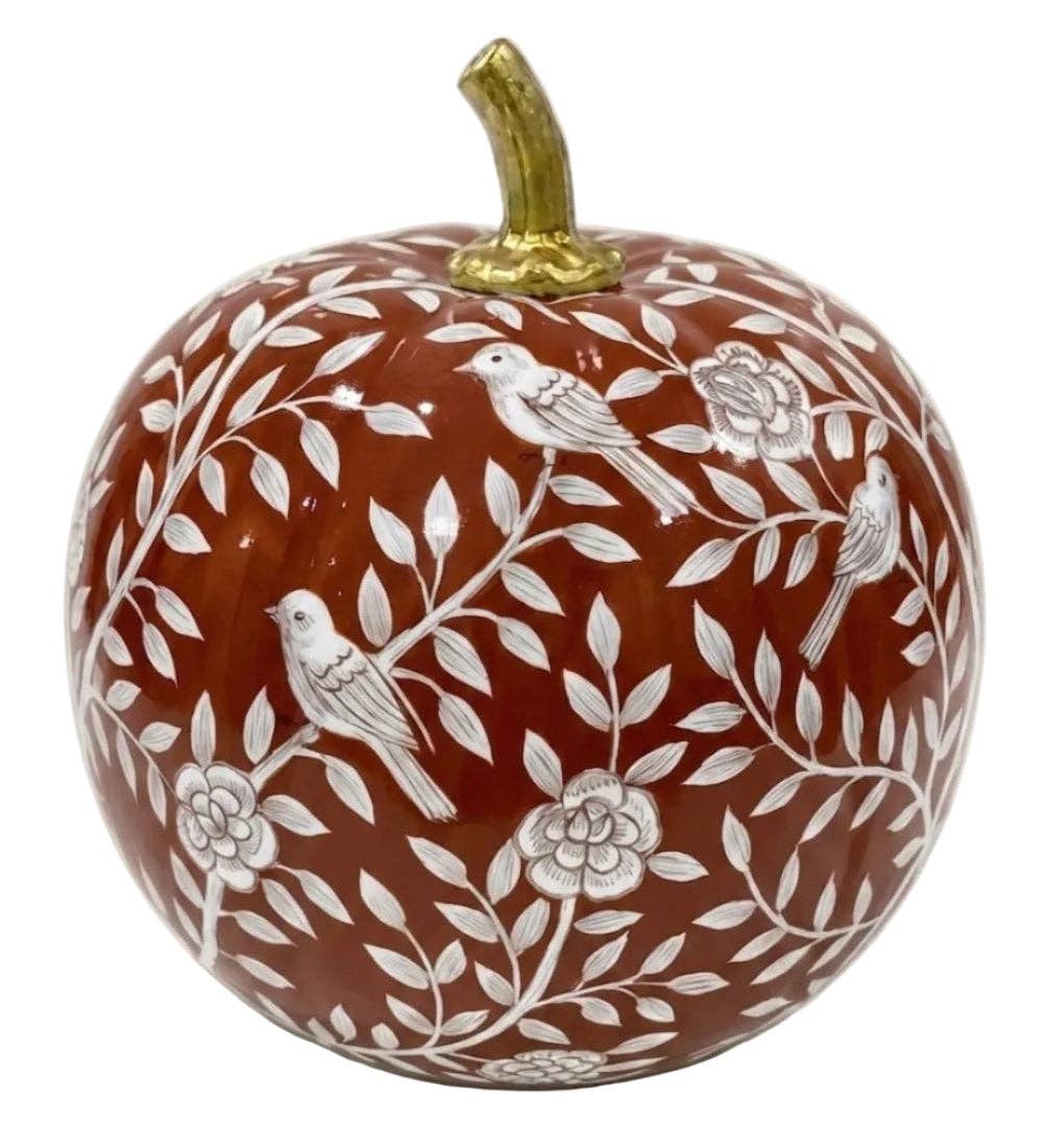 A decorative pumpkin ornament with a glossy reddish-brown base, featuring white floral and leaf patterns, three white birds, and a metallic gold stem, shown on a plain white background.