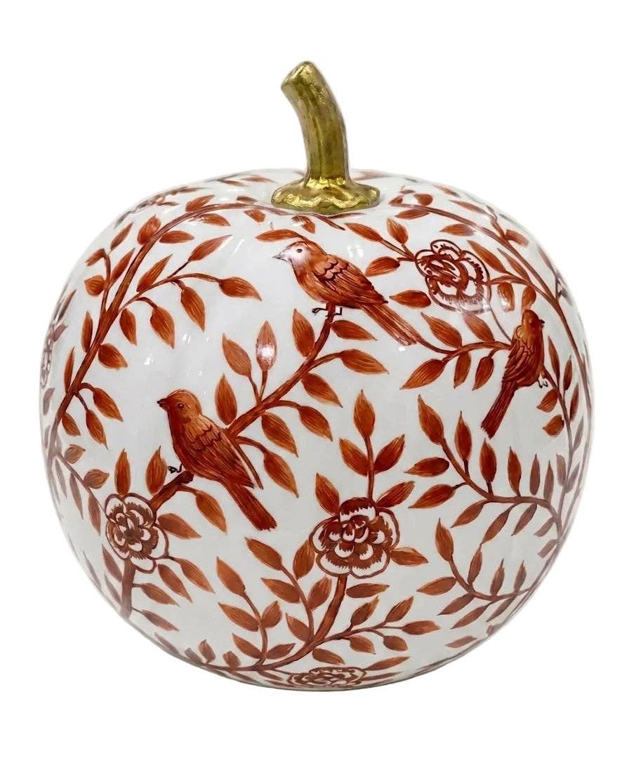 A decorative ceramic pumpkin with a white base decorated with a brown floral and bird pattern, featuring three small birds and a gold-colored stem.