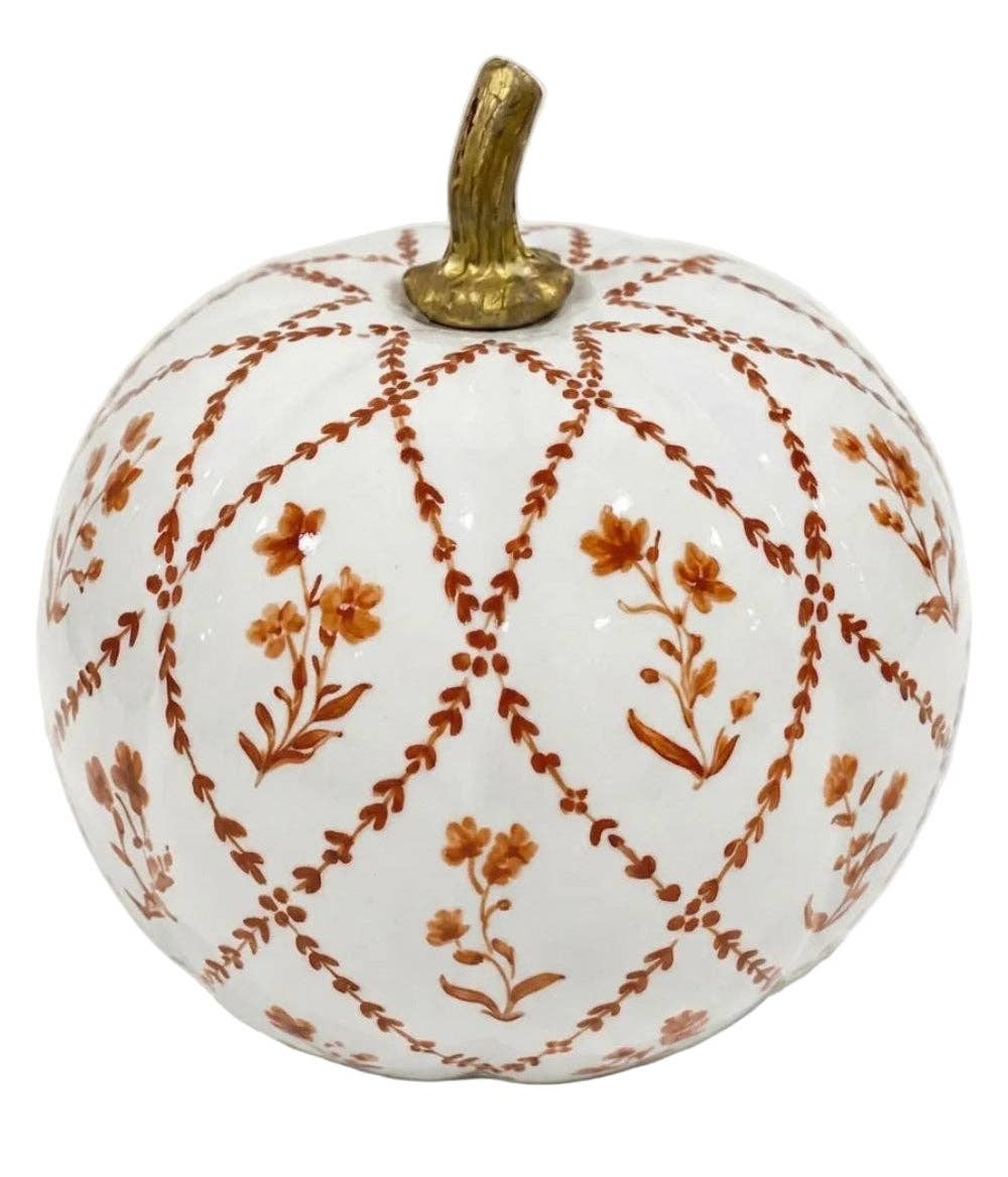 A decorative ceramic pumpkin with a white glaze, featuring a rust-orange floral and lattice pattern, and a metallic gold stem, shown on a plain white background.