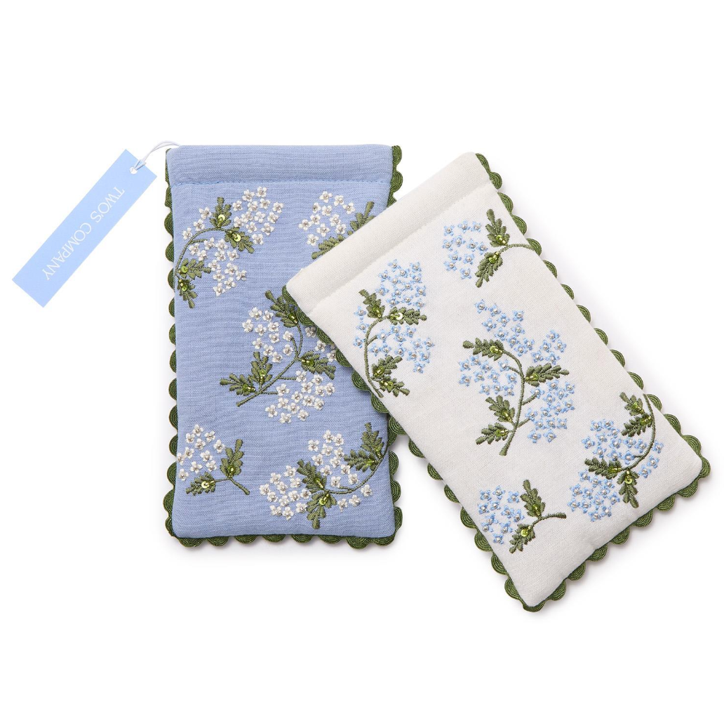 Two embroidered eye glasses holders with floral patterns on a white background
