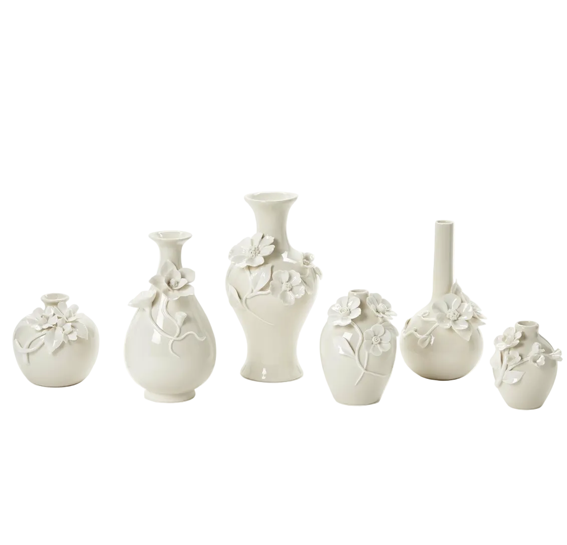A set of six small ceramic vases in a warm off-white or cream color, decorated with raised floral and leaf motifs, arranged against a plain white background.