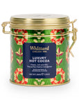 A cylindrical metal tin of Whittard Luxury Hot Cocoa with a gold lid and handles, featuring a green patterned label with red and yellow motifs and a dark blue central label.
